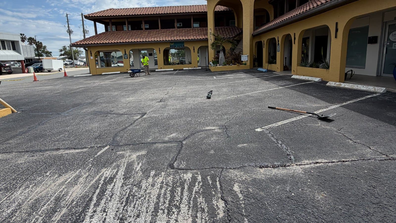Commercial parking lot before sealcoat, showing cracked and patched asphalt